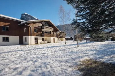 a snow covered yard in front of a house at Appartement rénové T2, vue montagne in Samoëns