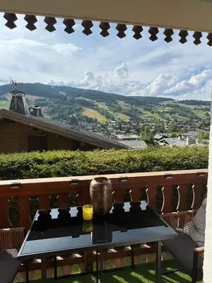 a table on a balcony with a view of a city at Très bel appartement avec parking gratuit in Megève