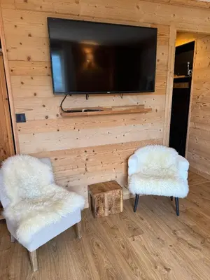 a living room with two white chairs and a flat screen tv at Très bel appartement avec parking gratuit in Megève