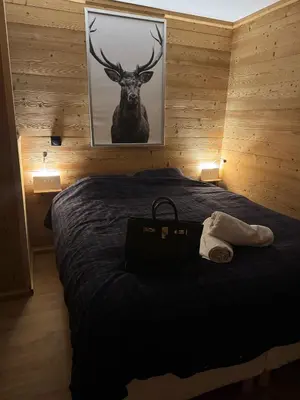 a bedroom with a bed with a deer picture on the wall at Très bel appartement avec parking gratuit in Megève