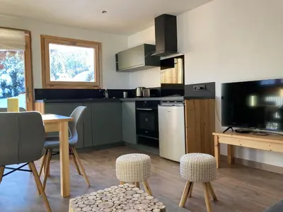 a kitchen with a table and some chairs and a television at Renovated flat facing Mont Blanc in Combloux