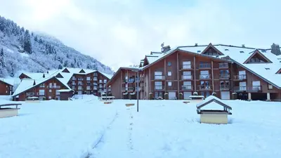 a large building with snow on the ground in front at Studio au pied des remontées/wifi/smart TV/parking in Les Contamines-Montjoie