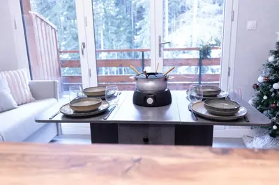 a table with plates and a pot and a christmas tree at Studio cabine Au Loup Blanc avec vue Mont Blanc in Saint-Gervais-les-Bains