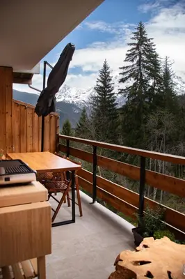 a balcony with a table and a view of a mountain at Studio cabine Au Loup Blanc avec vue Mont Blanc in Saint-Gervais-les-Bains