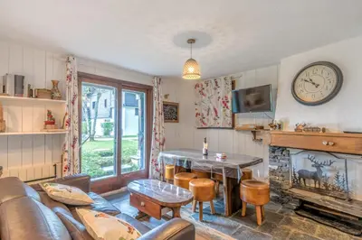 a living room with a couch and a table and a clock at Appartement Sous-Bois - Welkeys in Chamonix-Mont-Blanc