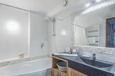 a bathroom with a tub and a sink and a tub and a mirror at Appartement Sous-Bois - Welkeys in Chamonix-Mont-Blanc