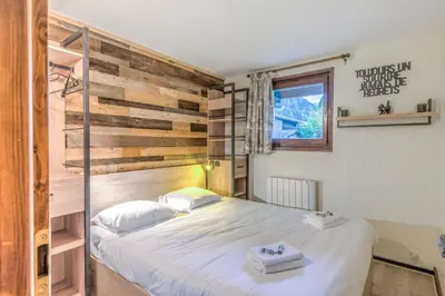 a bedroom with a bed and a wooden wall at Appartement Sous-Bois - Welkeys in Chamonix-Mont-Blanc
