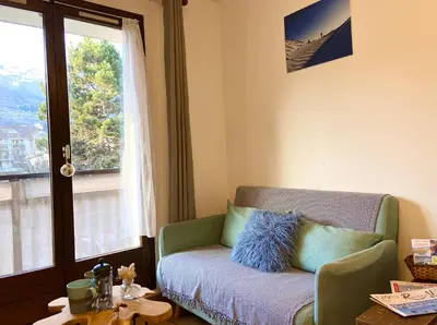 a living room with a green couch and a window at Le refuge 'Les 4 têtes' - balcon - vue montagne - proche centre & gare in Sallanches