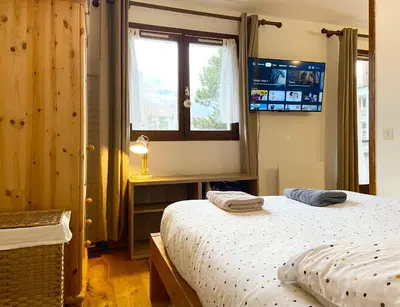 a bedroom with a bed and a window and a television at Le refuge 'Les 4 têtes' - balcon - vue montagne - proche centre & gare in Sallanches