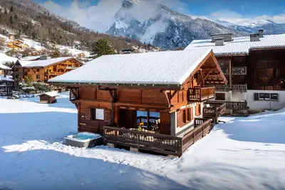 a log cabin in the snow with mountains in the background at Chalet Timothy - OVO Network in Samoëns