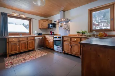 a large kitchen with wooden cabinets and a window at Chalet Timothy - OVO Network in Samoëns