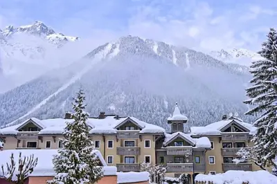 a large building with a mountain in the background at Résidence La Ginabelle - maeva Home - Appartement 3 pièces 6 personnes - Prestige MAE-7151 in Chamonix-Mont-Blanc