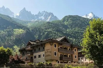 a large apartment building with mountains in the background at Résidence La Ginabelle - maeva Home - Appartement 3 pièces 6 personnes - Prestige MAE-7151 in Chamonix-Mont-Blanc