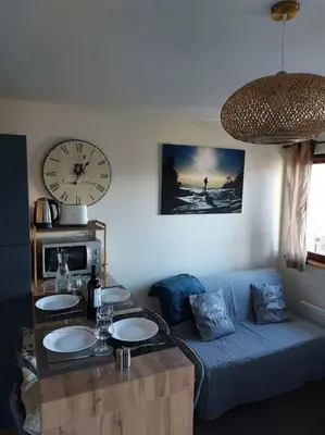 a living room with a couch and a clock on the wall at Appartement Saint Gervais proche centre in Saint-Gervais-les-Bains
