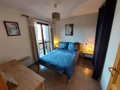 a bedroom with a blue bed and a table at Appartement Saint Gervais proche centre in Saint-Gervais-les-Bains