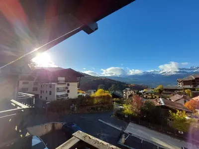 a view from a balcony of a city with the sun shining at Appartement Saint Gervais proche centre in Saint-Gervais-les-Bains