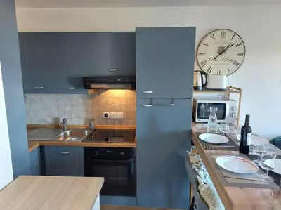 a kitchen with a clock on the wall and a counter at Appartement Saint Gervais proche centre in Saint-Gervais-les-Bains