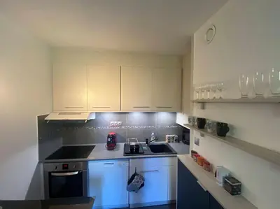 a small kitchen with white cabinets and a stove at Appartement, au cœur de Sallanches in Sallanches