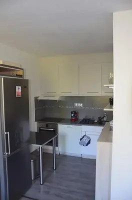 a kitchen with white cabinets and a black refrigerator at Appartement, au cœur de Sallanches in Sallanches