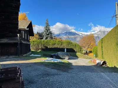 a car parked in a driveway with mountains in the background at Chalet du Bonheur in Saint-Gervais-les-Bains