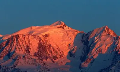 a snow covered mountain with the sun shining on it at Chalet Anatole - Vue Mont Blanc Exceptionnelle in Saint-Gervais-les-Bains