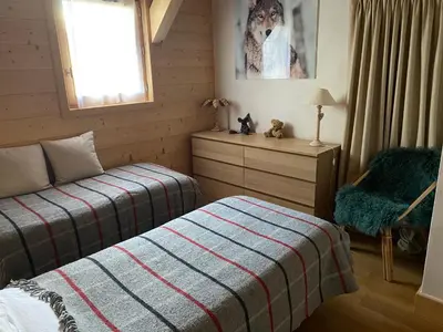 a bedroom with a bed and a chair and a window at Chalet Charline in Combloux