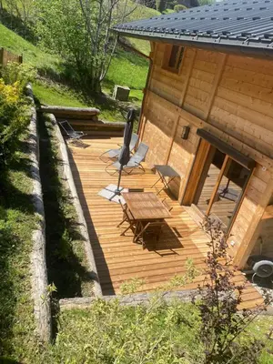 a wooden deck with a table and chairs next to a house at Chalet Charline in Combloux
