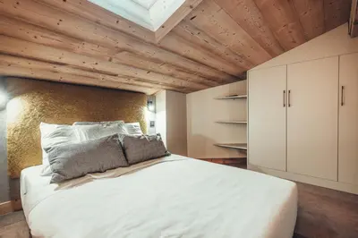 a bedroom with a large white bed and wooden ceilings at Appartement Keraos - Perfect for a family holiday in Megeve in Megève