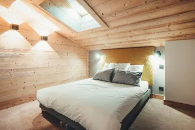 a bedroom with a large bed in a wooden wall at Appartement Keraos - Perfect for a family holiday in Megeve in Megève