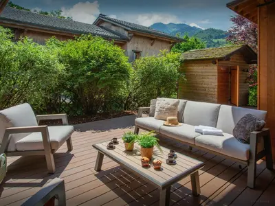 a patio with a couch and chairs on a wooden deck at Chalet Evonyx - OVO Network in Samoëns