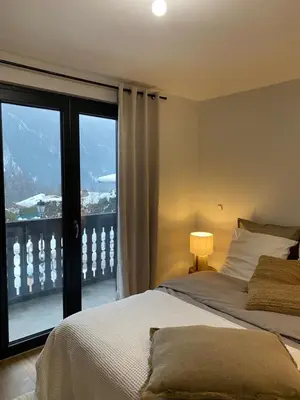 a bedroom with a bed and a large window at Appartement PISTE ROUGE in Les Houches