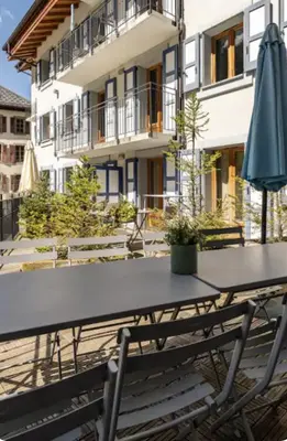 a table with an umbrella in front of a building at Loriaz 12 - Appartement avec vue et piscine à deux pas du telecabine in Vallorcine