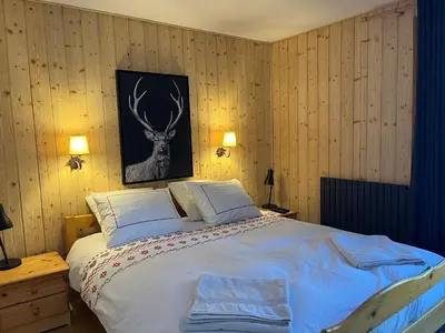 a bedroom with a bed with a deer picture on the wall at Chalet L'AS DE CARROZ in Arâches-la-Frasse