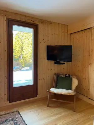 a room with a television and a chair and a window at Chalet L'AS DE CARROZ in Arâches-la-Frasse