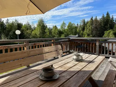 a wooden deck with a bench and an umbrella at Chalet L'AS DE CARROZ in Arâches-la-Frasse