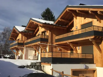 a large wooden house with snow on the ground at Appartement Rêve de Montagne in Samoëns