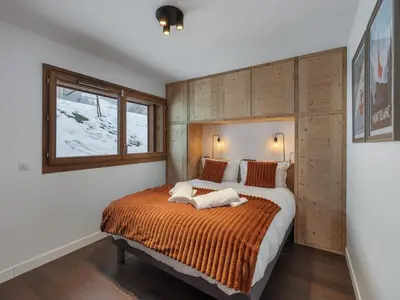 a bedroom with a large bed with an orange blanket at Appartement spacieux à Megève, 3 ch, près des pistes, parking privé - FR-1-569-139 in Megève