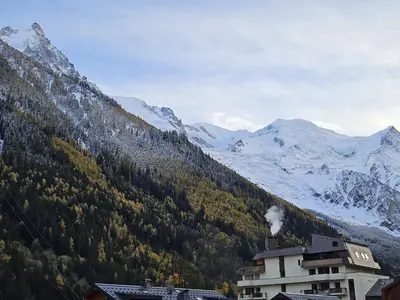 a building with smoke coming out of it next to a mountain at Appartement Cosy, Vue Mont Blanc, Plein Centre in Chamonix-Mont-Blanc