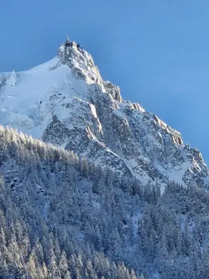a snow covered mountain with a house on top of it at Appartement Cosy, Vue Mont Blanc, Plein Centre in Chamonix-Mont-Blanc