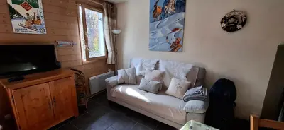 a living room with a white couch and a television at Charmant appartement T3 avec magnifique vue in Saint-Gervais-les-Bains