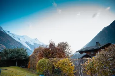 a house on a hill with mountains in the background at Chalet la Pagode, vue Mont-Blanc et jardin privé in Chamonix-Mont-Blanc