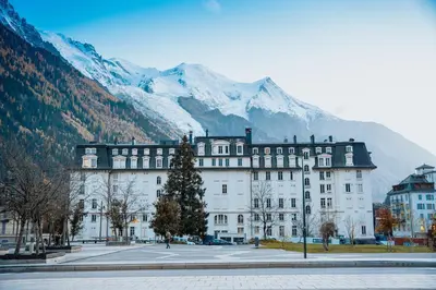 a large white building with mountains in the background at Chalet la Pagode, vue Mont-Blanc et jardin privé in Chamonix-Mont-Blanc