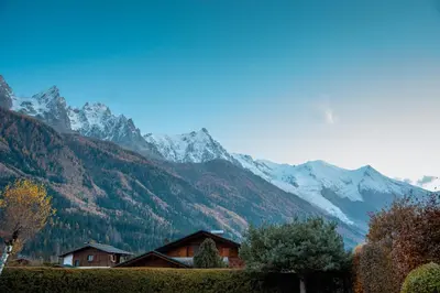 a house in front of a mountain with snow at Chalet la Pagode, vue Mont-Blanc et jardin privé in Chamonix-Mont-Blanc
