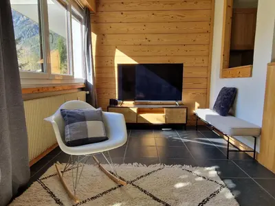 a living room with a tv and a couch and chairs at Les Tussilages - Terrasse vue Mont-Blanc in Chamonix-Mont-Blanc