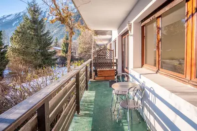 a porch with two chairs and a table on a balcony at Les Tussilages - Terrasse vue Mont-Blanc in Chamonix-Mont-Blanc
