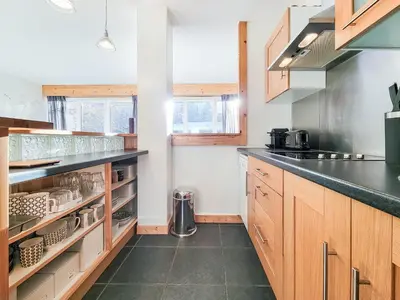 a kitchen with wooden cabinets and a black counter top at Les Tussilages - Terrasse vue Mont-Blanc in Chamonix-Mont-Blanc