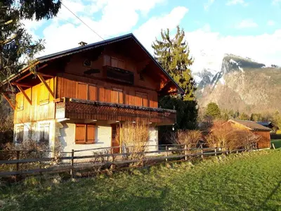 a house in a field with a mountain in the background at Appartement T4 au calme avec jardin et wifi, proche du centre et ski-bus - FR-1-624-150 in Samoëns