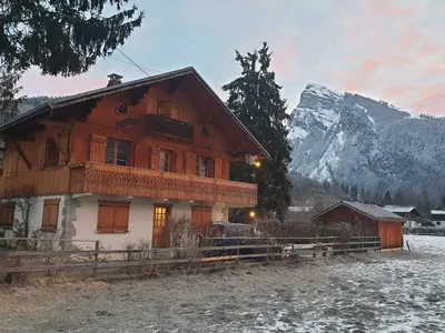 a wooden house with a mountain in the background at Appartement T4 au calme avec jardin et wifi, proche du centre et ski-bus - FR-1-624-150 in Samoëns