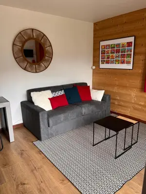 a living room with a gray couch and a mirror at Appartement cosy avec vue exceptionnelle in Saint-Gervais-les-Bains
