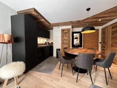 a kitchen and dining room with a wooden table and chairs at Appartement de standing 3P au pied des pistes, terrase privée, parking, à 350m du centre-village - FR-1-572-294 in Arâches-la-Frasse
